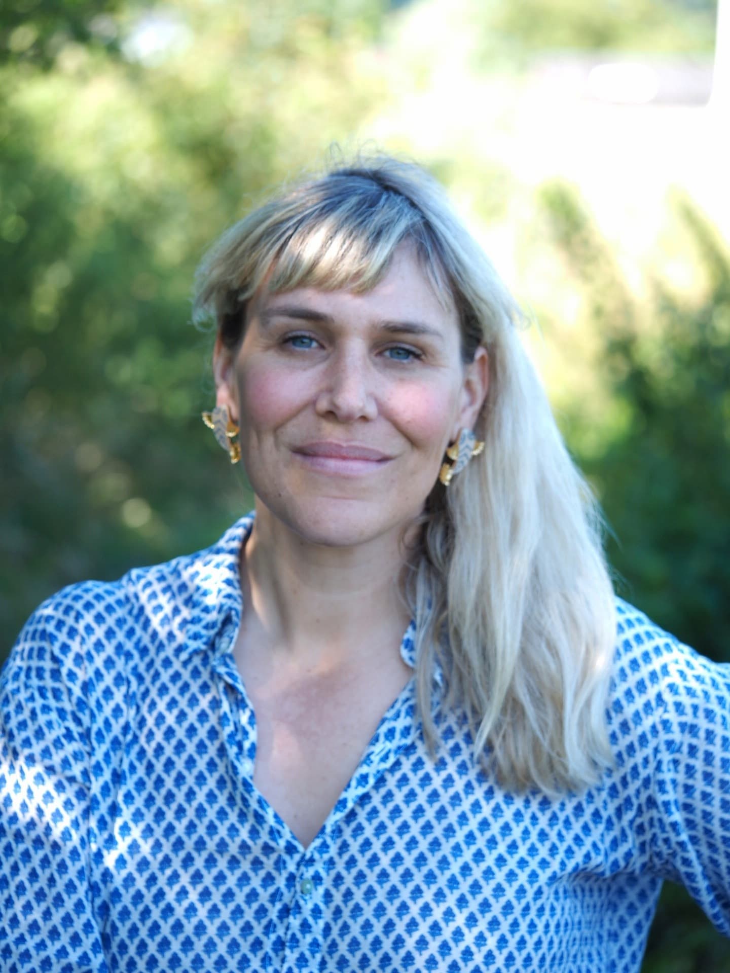 A headshot of a blonde woman against a green background