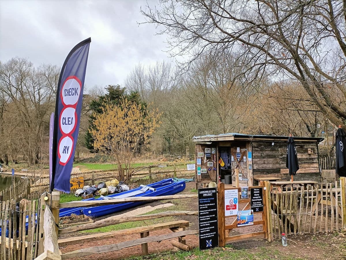 A flag saying 'Check, Clean, Dry' at a waterway with boats in the background.